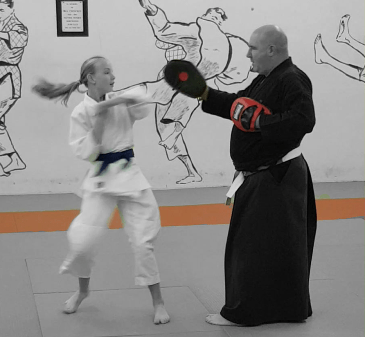 Child demonstrating a spinning hammer fist strike against a focus mit